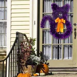 Detail showing a purple tinsel cat-shaped Halloween wreath with vibrant orange bow on a front door