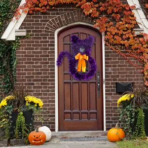 Purple tinsel cat wreath with orange bow displayed on a rustic wooden front door