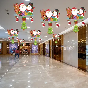 Festive Christmas hanging ornaments with Santa and snowman motifs in a shopping mall setting.