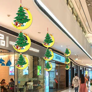 Festive Christmas tree and moon hanging decorations displayed in a shopping mall ceiling.