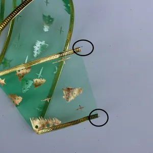 Macro detail showing the wired edge of a green Christmas ribbon with gold tree prints
