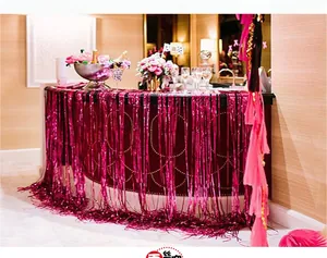 Vibrant magenta foil fringe curtain decorates a bar counter for a festive party setting.