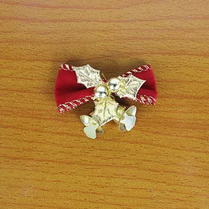 Detailed view of a red velvet Christmas bow featuring golden bells and holly leaves.