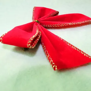 Detailed close-up view of a festive red velvet Christmas bow with gold metallic edge stitching