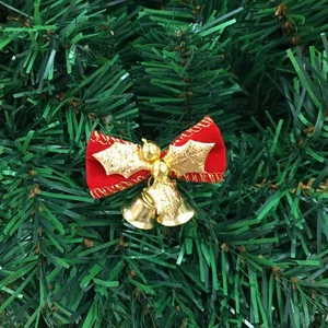 Close-up of red velvet Christmas bow with gold holly leaves and bells on tree