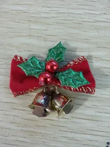 Detail of a mini Christmas red velvet bow with golden bells and green holly leaves decoration.