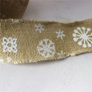 Nahaufnahme von natürlichem Juteband mit weißen Schneeflocken für die Weihnachtszeit