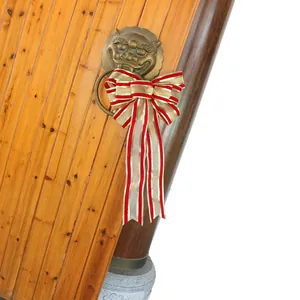 Large Christmas gold and red striped bow ornament hanging on a traditional door knocker