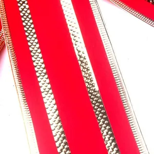 Close-up of festive red Christmas ribbon with decorative gold edges and mesh patterns.