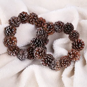 Detailed view of two heart-shaped natural pine cone Christmas wreaths on white fleece fabric