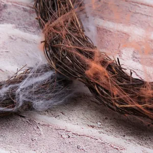 Close-up detail of Halloween vine wreath with orange and white artificial cobwebs.