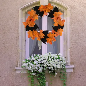 Halloween wreath with orange maple leaves and black bats on a white window frame