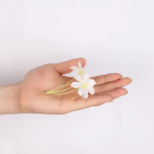 Close-up van kleine kunstmatige witte bloemen in de hand voor DIY ambachtelijke decoratie