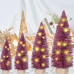 Kleine magentafarbene Weihnachtsbäume mit warmen LED-Lichterketten und Holzsockeln