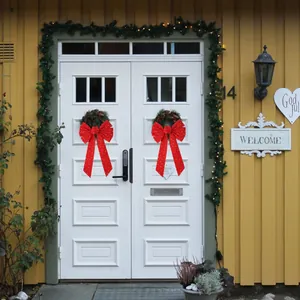 Large red velvet Christmas bows with gold star patterns on a festive white front door