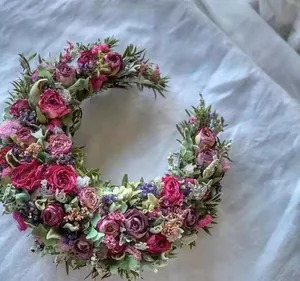 Detailed view of handmade crescent moon wreath with preserved pink roses and green leaves