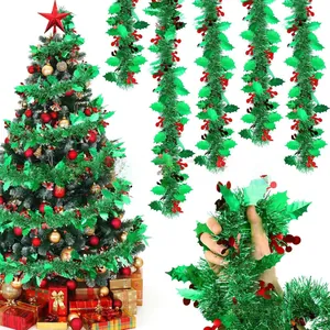 Close-up detail of festive green tinsel garland with red leaf accents for holiday decor