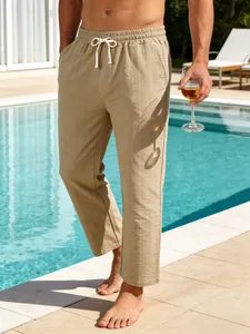Pantalon en lin rayé pour hommes présenté dans un magnifique cadre de piscine de luxe.