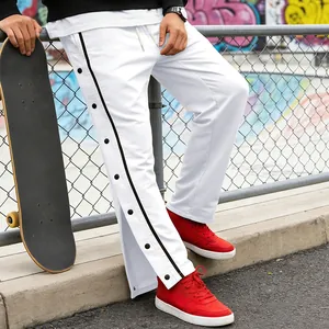 Dettaglio dei pantaloni sportivi bianchi da uomo con bottoni laterali e strisce