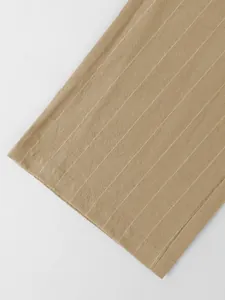 Gros plan sur la texture du tissu et l'ourlet du pantalon en lin à rayures