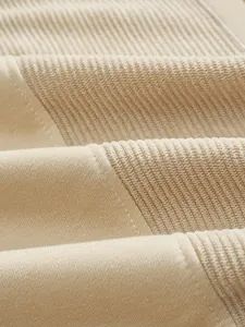 Dettaglio ravvicinato del tessuto patchwork in velluto a coste beige di una felpa da uomo