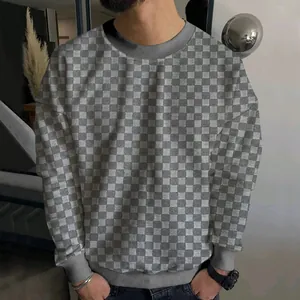 Close-up of men's grey and white checkerboard knit sweater featuring a ribbed crew neck line