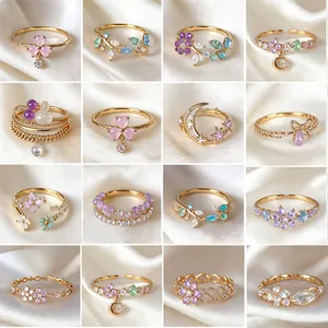 Collage di vari anelli regolabili in oro con zircone floreale e motivi stella luna.