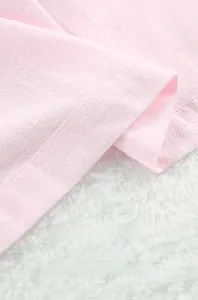 Détail macro montrant la texture du tissu respirant rose doux et les coutures du pyjama