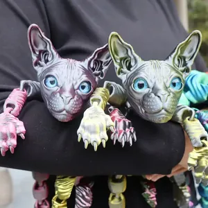 Detail of two 3D printed articulated Sphynx cat figures in vibrant purple and green colors.