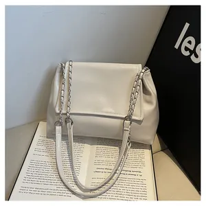 Detailed view of white shoulder bag with dual chain and leather strap design.
