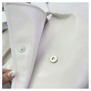 Close-up of silver magnetic snap closure on off-white minimalist shoulder bag