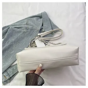 Macro view showing the bottom stitching and soft leather texture of the white handbag