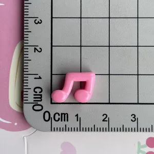 Close-up detail view of a mini pink music note resin charm shown on a centimeter scale ruler