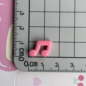 Close-up detail view of a mini pink musical note resin charm on a measurement grid