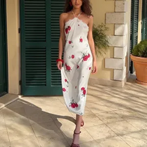 Elegant white halter neck summer dress with red rose floral print shown in outdoor setting