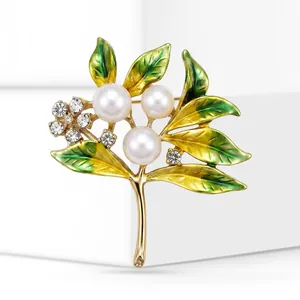 Close-up detail of enamel branch brooch with pearls and rhinestones on gold-toned alloy.