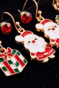 Close-up detail view of cartoon Santa Claus and gift box enamel Christmas earring set