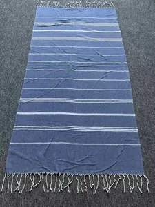 Detail view of a blue and white striped Turkish beach towel with elegant tassels