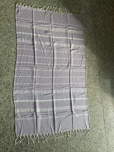 Full-length view of a purple striped Turkish beach towel with elegant white tassels.
