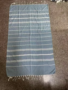 Detailed view of a blue and white striped Turkish beach towel with elegant tassels.