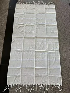 Flat lay of a white Turkish beach towel featuring elegant fringe detailing and stripes