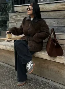 Street style view of a brown oversized sherpa jacket with drawstring waist and leather collar.