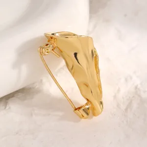 Detailaufnahme einer kreativen goldenen Blumenstrauß-Brosche mit Metallstruktur.