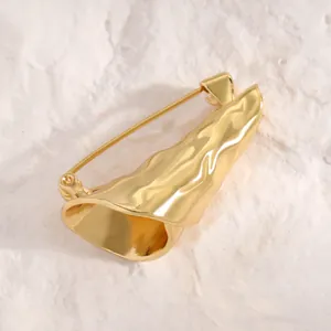 Nahaufnahme einer strukturierten goldenen Blumenstrauß-Brosche auf weißem Steinhintergrund.