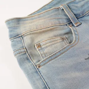 Close-up of blue denim jeans pocket with metal rivets and distressed wash detail.