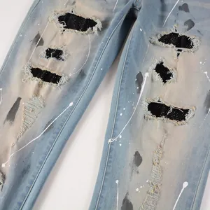 Close-up of distressed denim jeans with black rhinestone patches and paint splatters