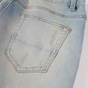 Close-up detail of the back pocket and stitching on light blue slim fit distressed jeans