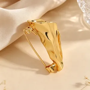 Close-up detail of a gold artistic brooch with unique sculpted organic folds