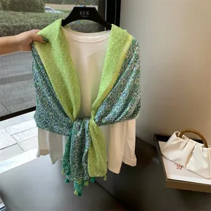 Détail de l'écharpe à fleurs vert citron et glands sur un t-shirt blanc.