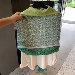 Détail du motif floral vert complexe sur un châle d'été léger avec des glands doux
